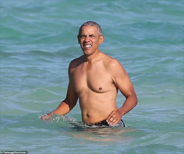 Barack Obama takes a dip in Hawaii, as daughters Sasha and Malia hit the water on paddleboards